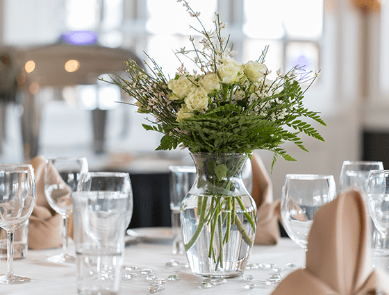 white flowers in a vase on a fully set table